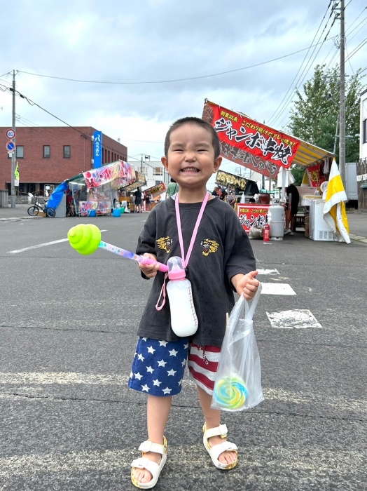 お祭りの露店を背景に写る男の子